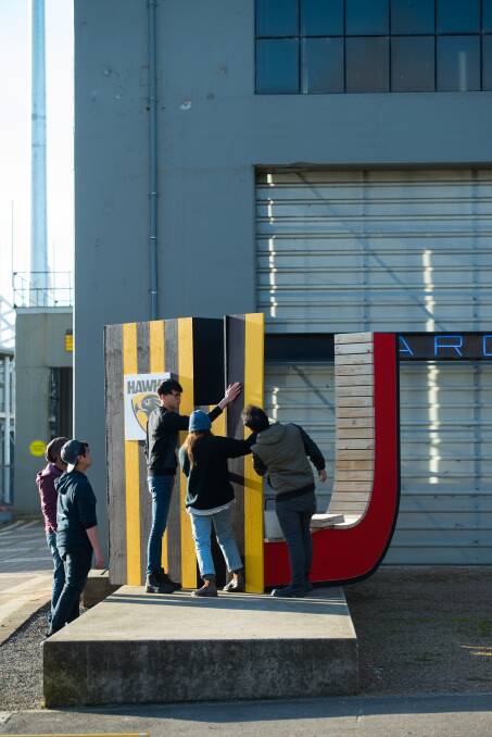 ILLUSION: Students at the University of Tasmania work on UTAS and Hawks signage ahead of the University Open Day in August. The signs are different depending on which way you look. Picture: Scott Gelston