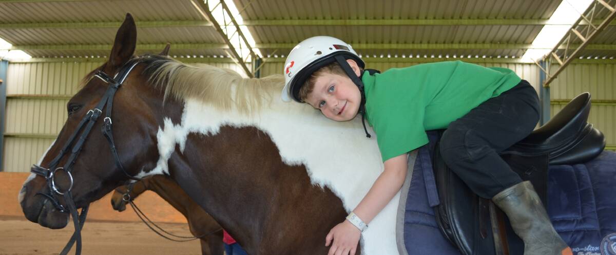 Bonding: Giant Steps student Elliott Bartninkatis gives his mount Maisy a hug for doing a great job. Horse therapy has proven to be beneficial to children with Autism Spectrum Disorder.