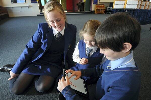 Year 6 Larmenier Primary School pupil Madeline Robinson, 12, helps year 3 pupils Kelsey Walsh and Patrick Dewar, both 8, try out their new iPads. Picture: GEOFF ROBSON
