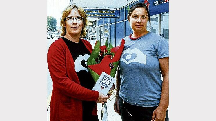 Mara Schneiders and Bel St Clair deliver red roses to the electoral office of Andrew Nikolic in support of marriage equality. Picture: NEIL RICHARDSON