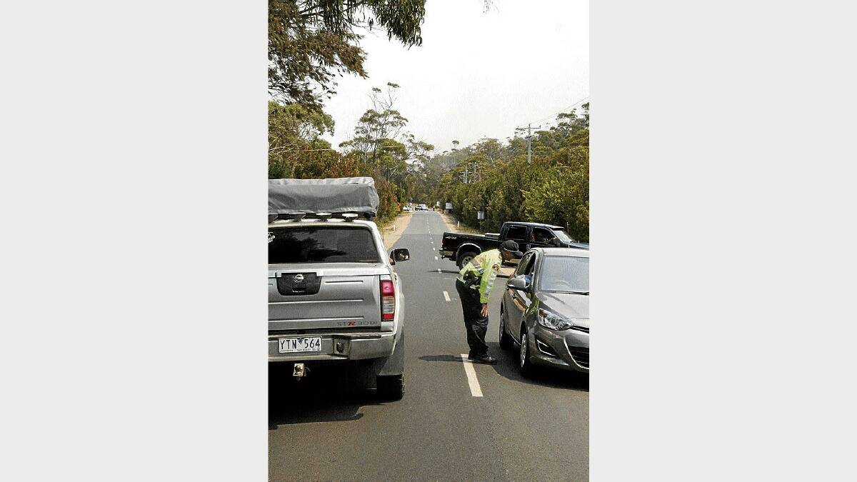 Sergeant Phil Summers stops south-bound traffic on the Tasman Highway just south of Bicheno yesterday.