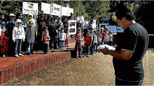 Aref Ghalandari reads from the Koran as members of the Hazara Community of Launceston gather in Civic Square yesterday. Picture: GEOFF ROBSON