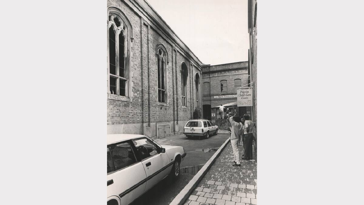 Churchgoers survey the fire damage of Pilgrim Uniting Church Hall on Paterson Street. December 8, 1985.