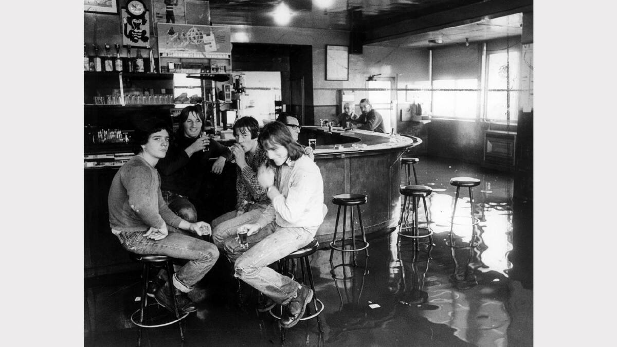 Drinkers carry on as usual, despite the flooded bar of the Inveresk Hotel in Dry Street. October 24, 1979.