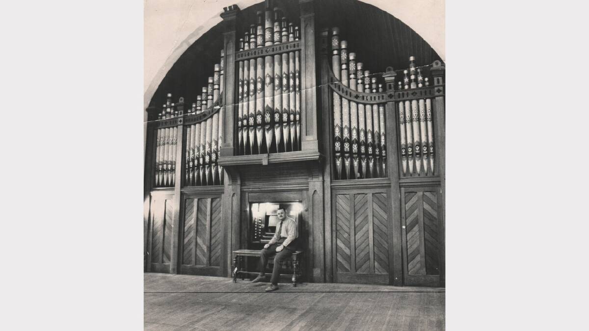 Albert Hall supervisor Carl Sinclair poses with the Hall's then 116-year-old water-powered organ. April 24, 1975.