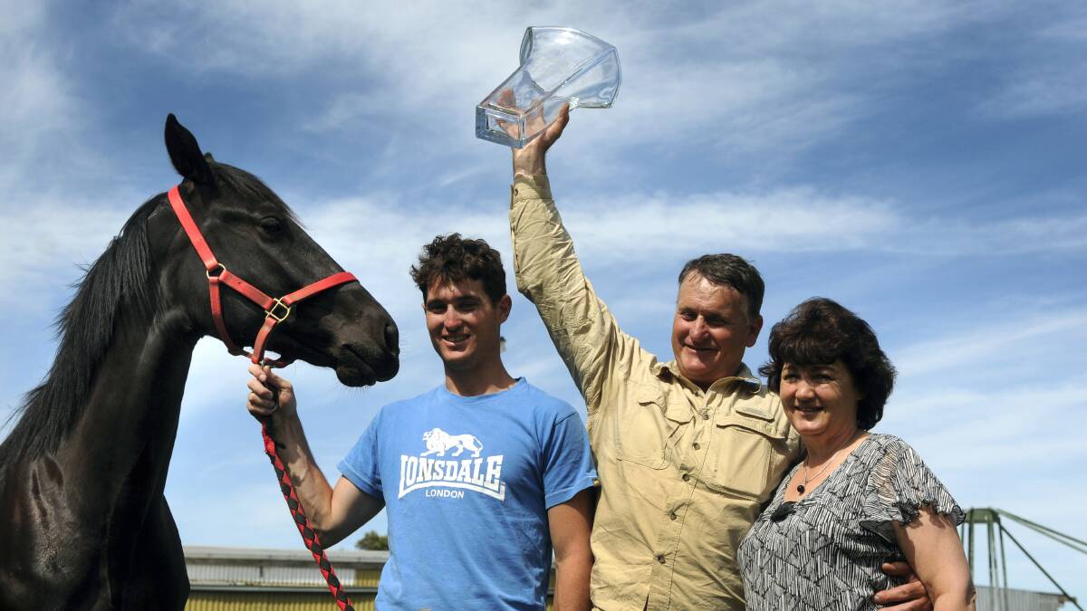 Todd Rattray holds pacer Beautide's unnamed sister, while Barrie Rattray, of Longford, lifts his Miracle Mile trophy with wife Denise. Picture: PAUL SCAMBLER