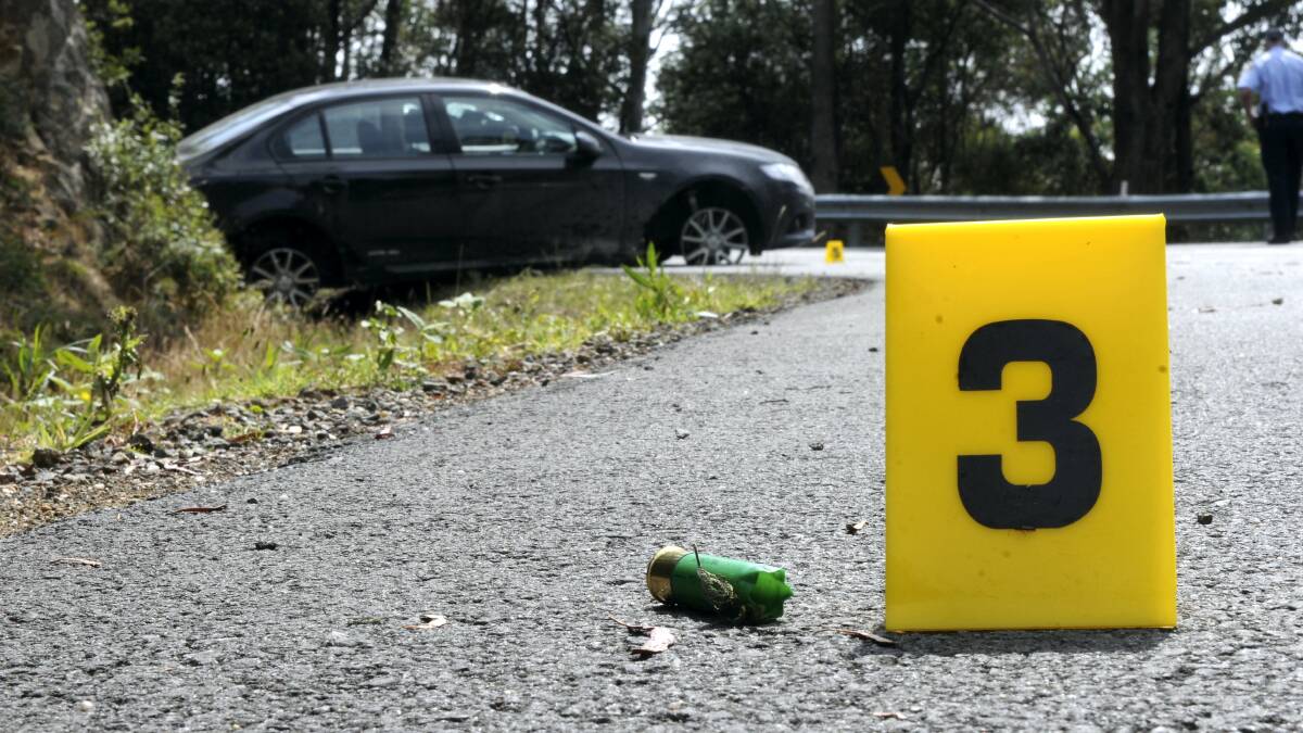 A shotgun cartridge is marked on Poatina Road near a late model Ford Falcon sedan allegedly involved in a police car chase yesterday.