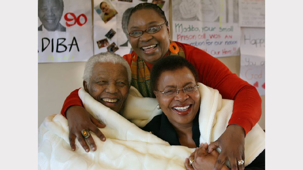 In this handout from Nelson Mandela Foundation, former South African president and Nobel peace prize laureate Nelson Mandela  and his wife Graca Machel share a laugh with Boniswa Qabaka (C) whilst wrapped up in a blanket, a gift received from the staff in honour his 90th birthday, at the Nelson Mandela Foundation August 5, 2008  in Houghton, Johannesburg