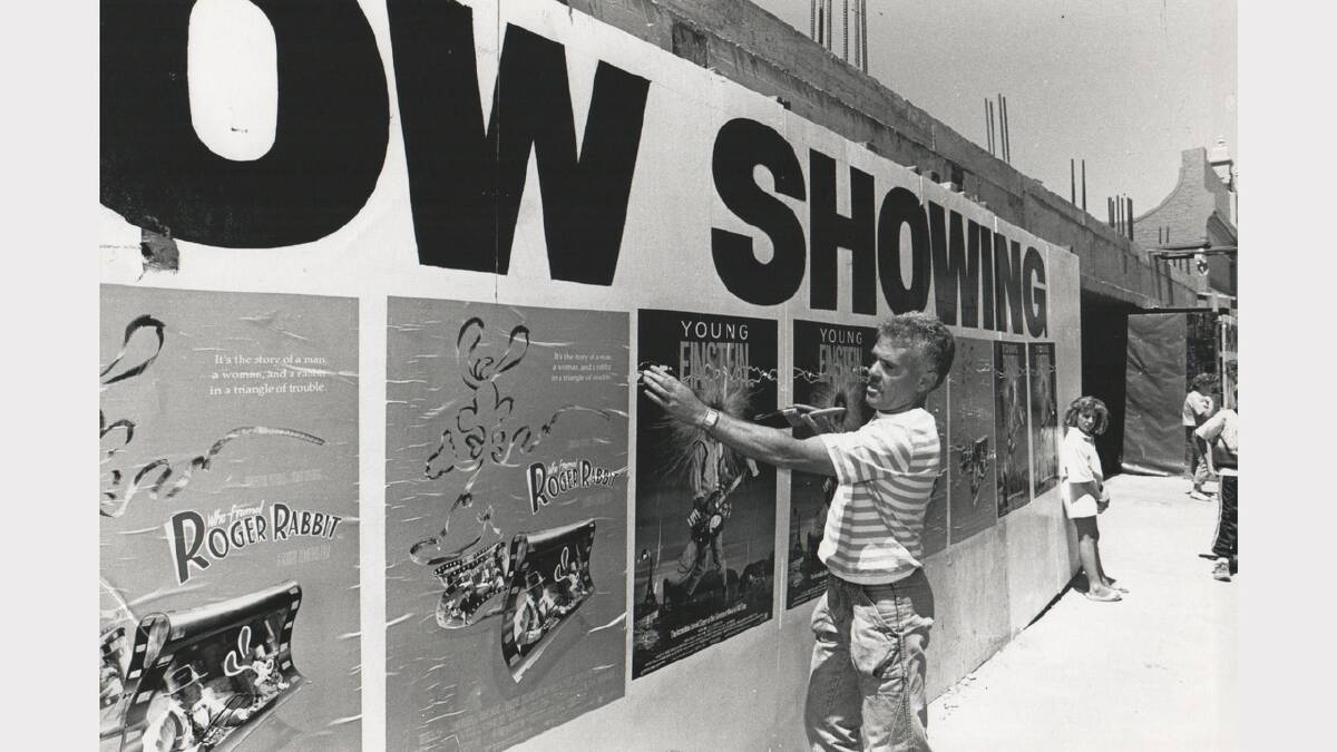 City Twin Cinemas manager David Heath hangs posters outside the reopened Village City Cinemas. Photo: December 1988.