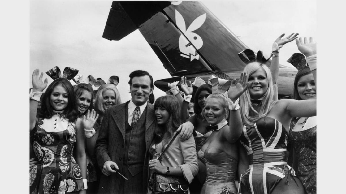 Hugh Hefner, American editor, publisher and founder of Playboy magazine, and his girlfriend Barbi Benton are welcomed by 'Bunny Girls' from the London Playboy Club, on their arrival at Heathrow Airport aboard his private DC 9 jetliner, which bears the Playboy logo. One Bunny Girl is wearing a Union Jack costume. 