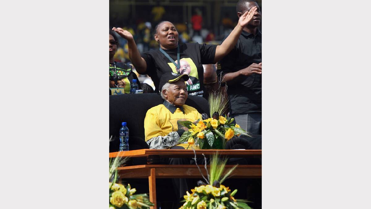 Former South African President Nelson Mandela sits on stage as ANC party members dance April 19, 2009 in Johannesburg, South Africa.