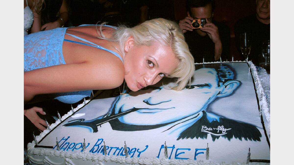 A model poses with Playboy founder Hugh Hefner's birthday cake at Barfly club to celebrate Hefner's 76th birthday March 29, 2002