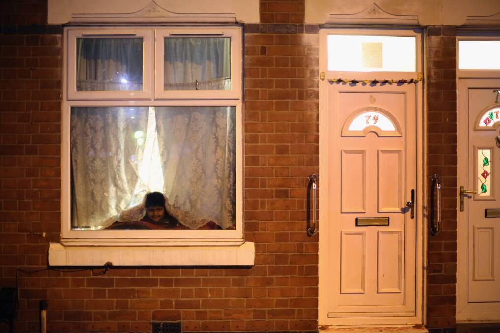 A young boy looks out from his home to watch fireworks during the Hindu festival of Diwali on November 13, 2012 in Leicester, United Kingdom. Photo by Christopher Furlong/Getty Images
