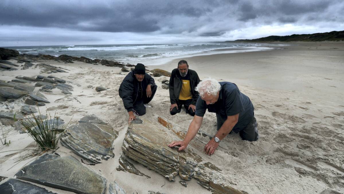 Tasmanian Aboriginal Centre chief executive Michael Mansell (at right) examines rock carvings at Sundown Point in the Tarkine with Rex Johnson and David Sainty.