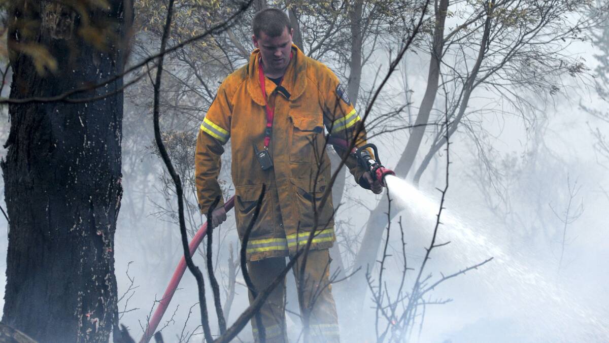 A firefighter helps put out a grass fire at Ravenswood yesterday.  Picture: MARK JESSER
