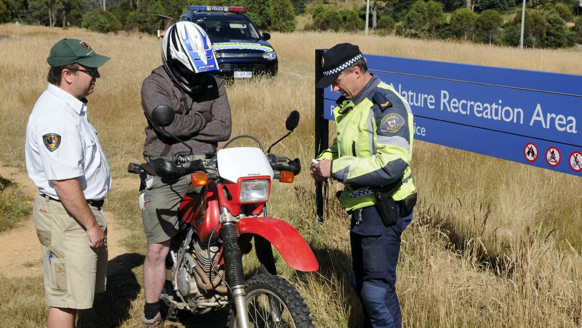Parks and Wildlife Service compliance officer Michael Spaulding and Senior Constable Steve Ockerby talk to a motorbike rider at Kate Reed Reserve. Picture: PAUL SCAMBLER