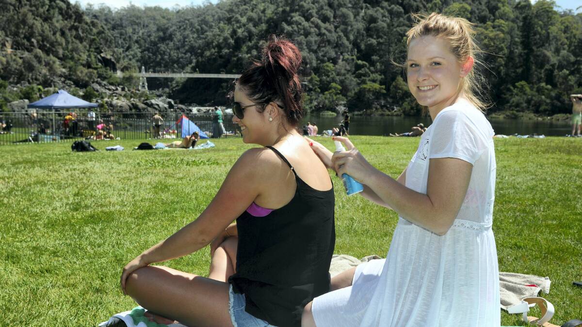 Chloe Guy, 22, and Jemma Goldsmith, 20, both of Launceston, apply sunscreen at the First Basin yesterday. Picture: PAUL SCAMBLER