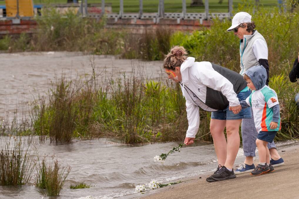 Amy Eberhardt, with her mum Vicki and son Darcy, places a flower in the South Esk River. Picture by Phillips Biggs