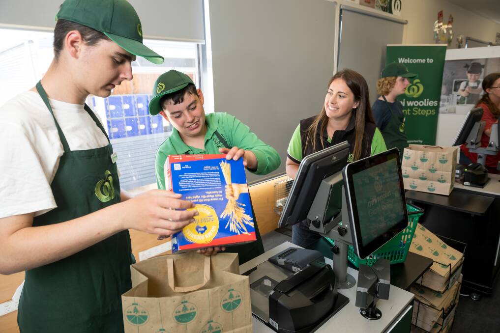 Ryan Barker and Josh Lowe packing groceries with grade 11-12 teacher Danielle Whatley. Picture by Phillip Biggs