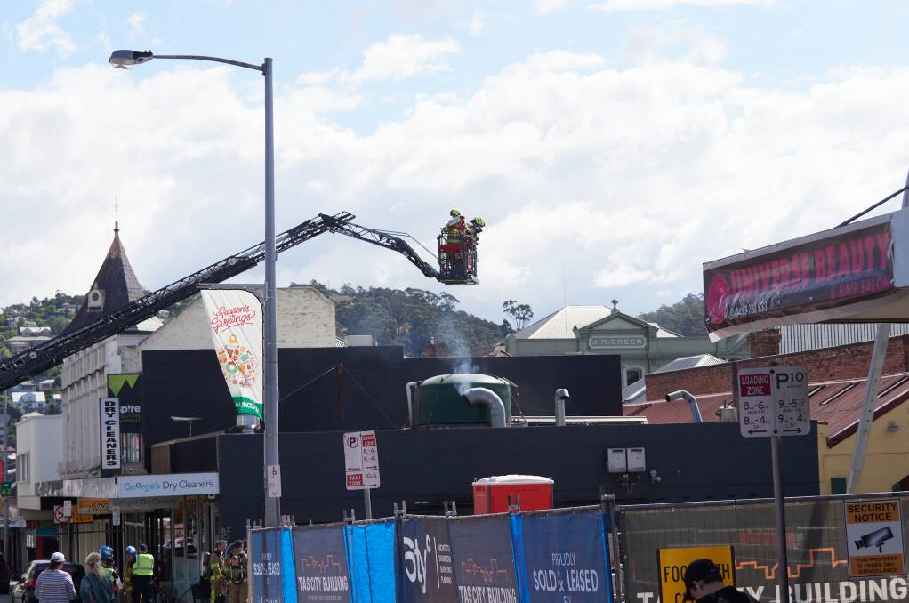 Fire crews use a crane to extinguish a fire at George's Dry Cleaners on York Street, Launceston. Picture by Rod Thompson