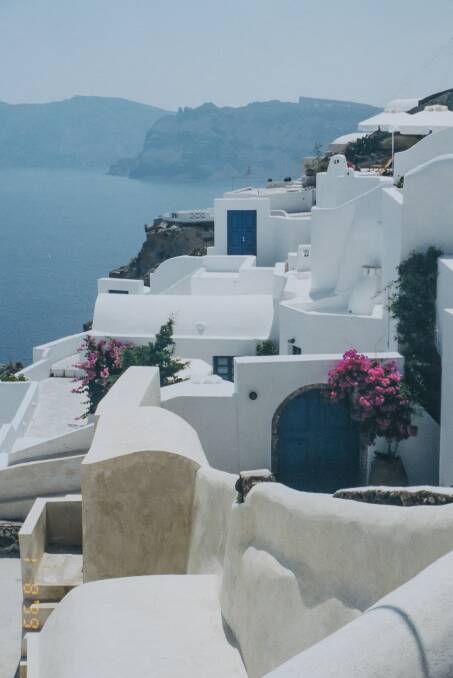 The white washed buildings and blue Aegean sea with a splash of bougainvillia pink