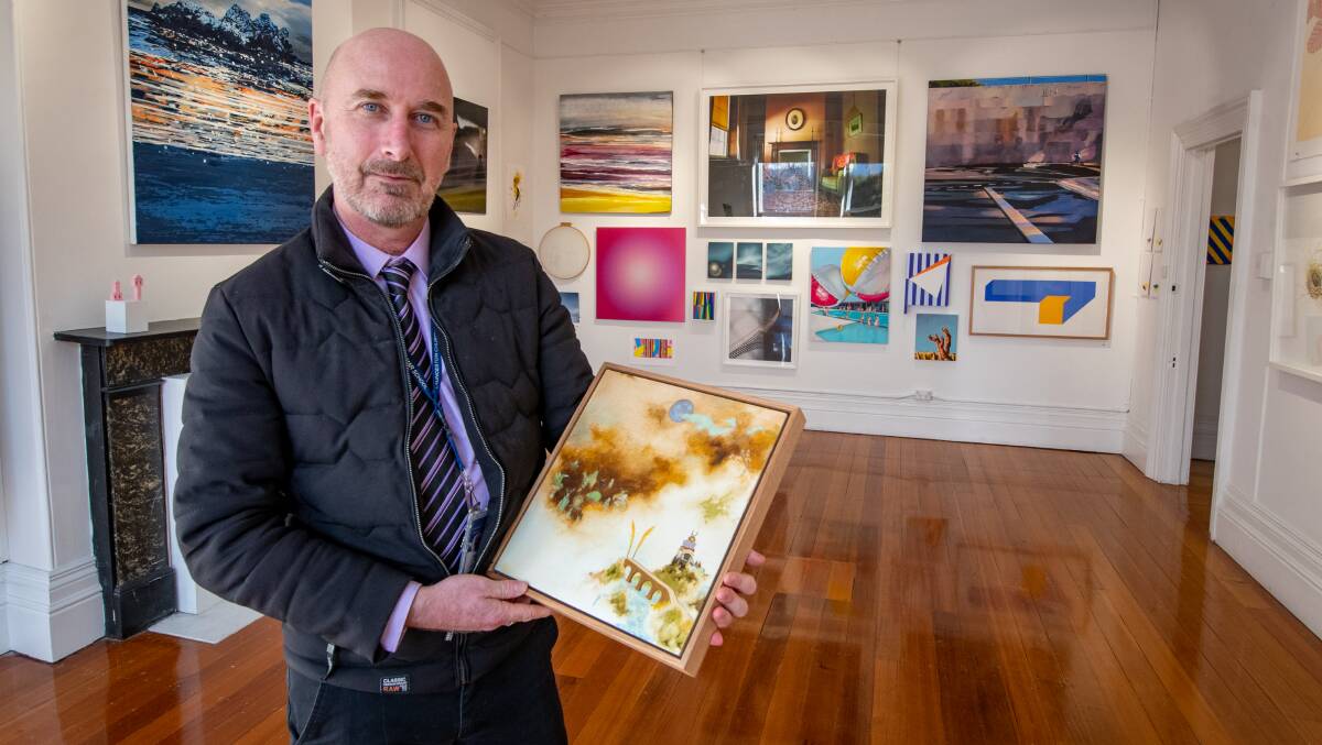 Paul Snell with a painting by Mark Rodda in the collective exhibition The Butterfly Effect at Poimena Gallery, Mowbray. Picture: Paul Scambler