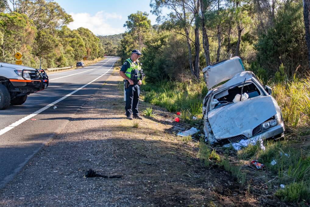 Acting SGT Tony Latham of George Town police looks at the silver Mitsubishi Magna in the ditch. Picture by Paul Scambler