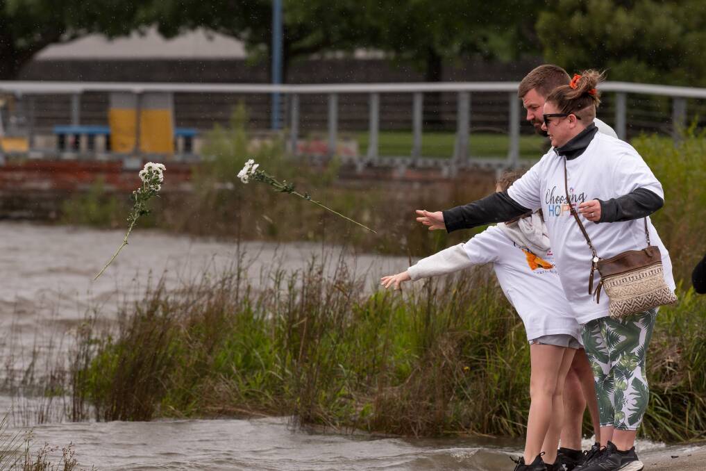 Bonnie, Dion and Trinity Saunders place a flower in the river at last year's Choosing Hope walk. Picture Phillip Biggs