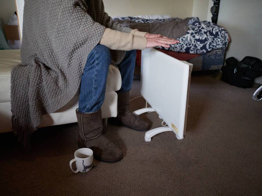 A man trying to warm his hands over a heater. Picture by Rod Thompson. 
