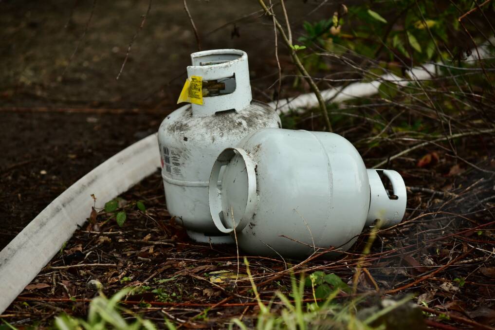 DANGER: Tasmania Fire Service officers removed gas cylinders from a Karoola home, which had been engulfed in flames.