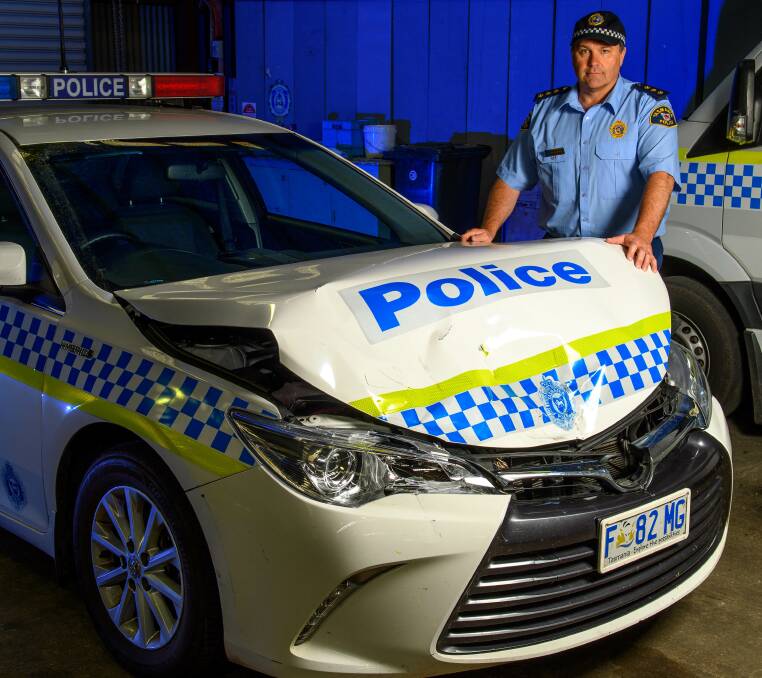 Launceston Inspector Darren Hopkins with one of two police cars damaged during an alleged evasion incident on Tuesday. Picture: Scott Gelston