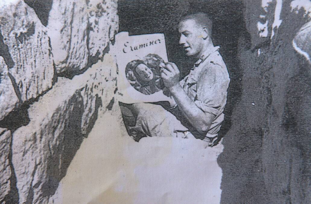 WAR STORIES: George Henderson pictured in the trenches in 1941 reading The Examiner.