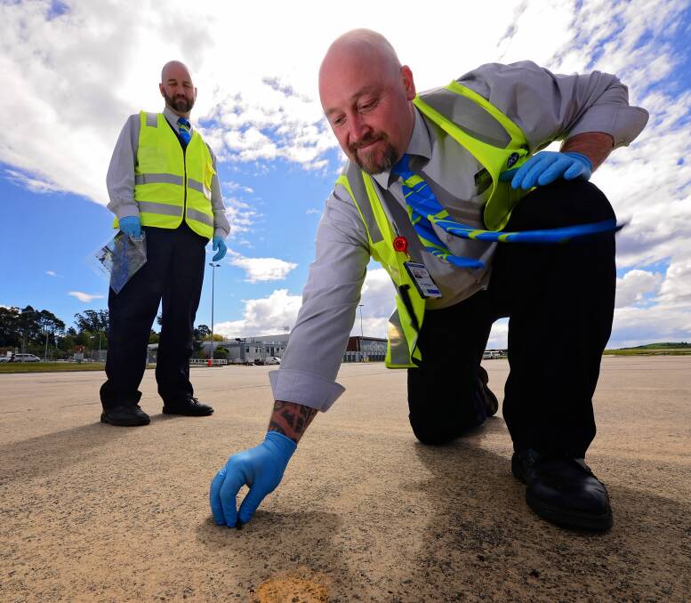 CLEAR-UP: ISS security officers Ged Parsons (right) and Rick Cash (left) inspect the apron at Launceston Airport for debris as part of Airport Safety Week. Picture: Phillip Biggs