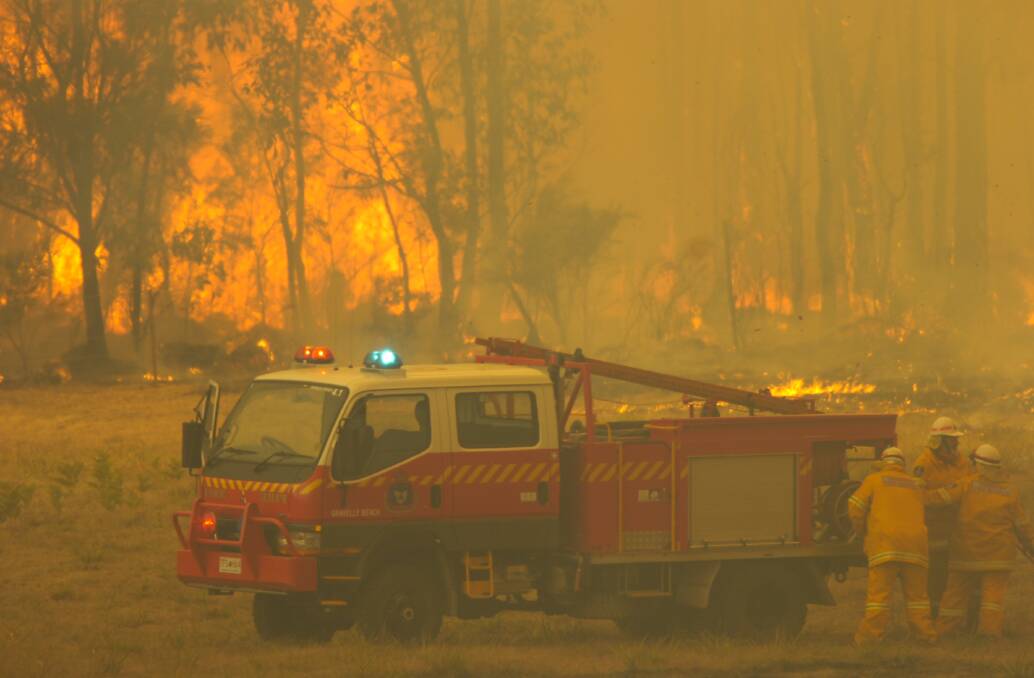 Fire fighters work at their fire truck as the fire rages on the East Tamarin in 2006. 