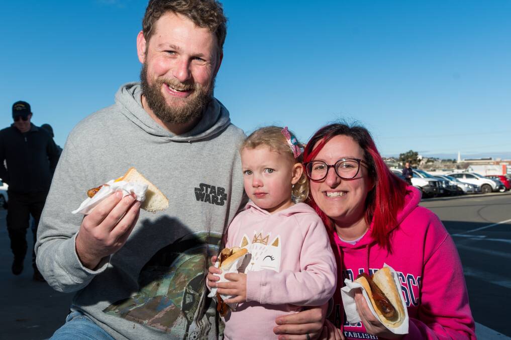 Tom, Courtney and Arabella Newman, of Riverside, enjoy the sausage sizzle as a family at Bunnings North Launceston. Picture: Phillip Biggs