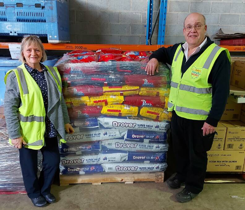 A Paw Up founder Deb Conley with former Loaves and Fishes warehouse manager Oswald Schneider collecting a pallet of donated dog food. Picture: supplied