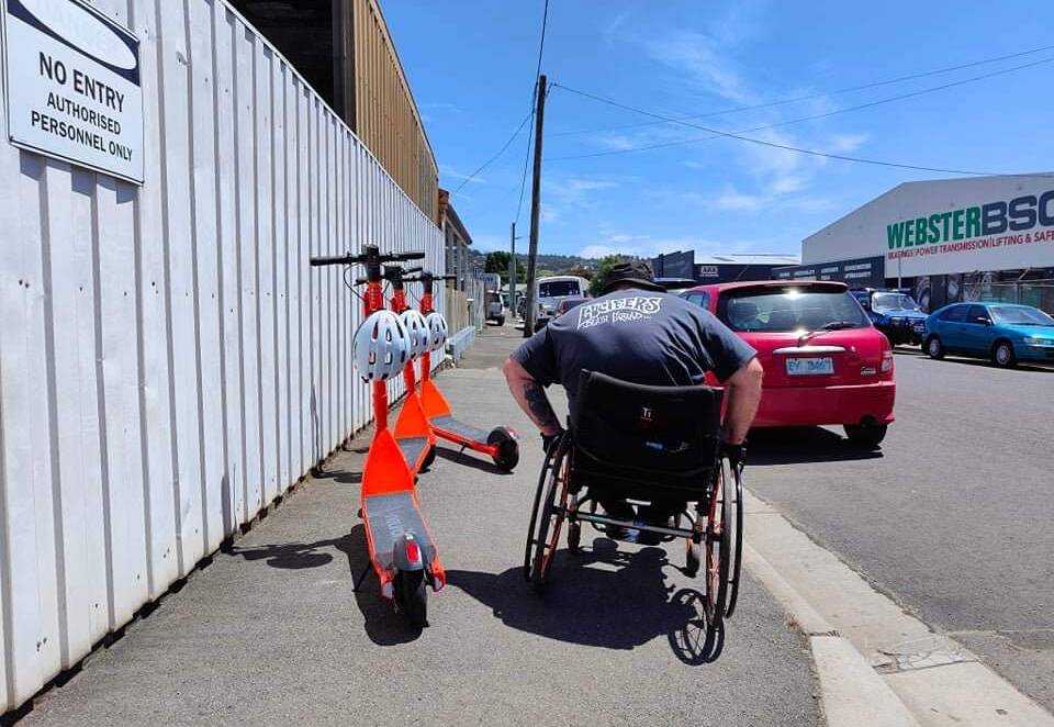 A Launceston man in a wheelchair navigates around parked e-scooters. Picture: Dr John Ralph