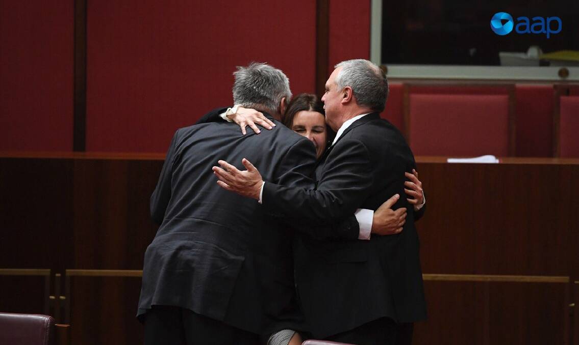Senator Jacqui Lambie embraces Centre Alliance senators Rex Patrick and Stirling Griff after voting in favour of the government's income tax plan this week. Picture: Lukas Cock/AAP