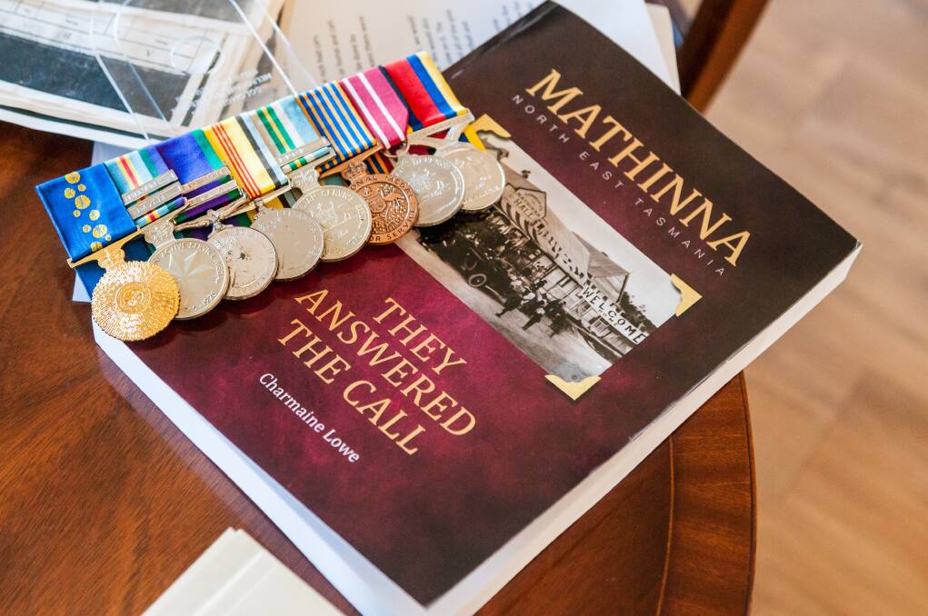 Moss Lowe OAM's war medals with Charmaine Lowe's completed work, Mathinna: They Answered the Call. Picture: Phillip Biggs