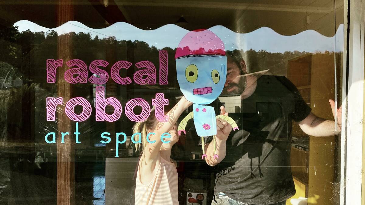 Stick 'em up: Artist Dan Kershaw with young Aaliyah Slocombe putting up the Rascal Robot signage. Picture: supplied