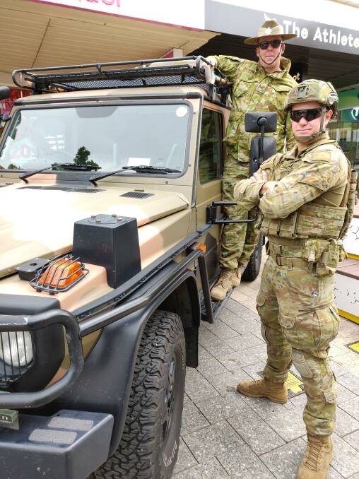 Green machines: Lance Corperal Nicholas Bowman with Corporal Simon Ward aboard a Mercedes Benz G-Wagon at the Brisbane Street Mall. Picture: Harry Murtough
