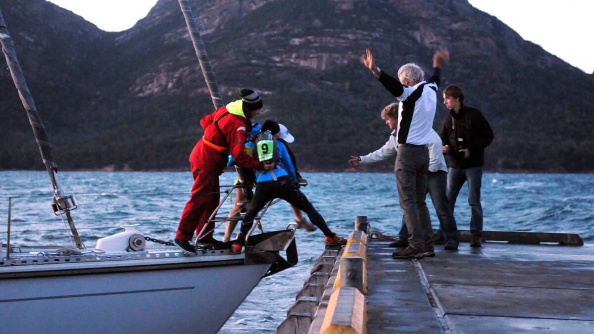 Three Peaks Race: Skipper Michael Crew and his team sailed Magic Miles into Coles Bay. Runners André Bartels and Justin Fonte both of WA, jump ashore to start their 35km run.
