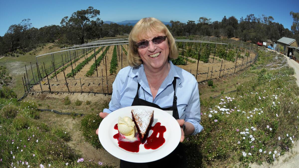 Kate Bradley with her "Humbleberry Pie" and the view across the strawberry patch at Kate's Berry Farm to the Freycinet Peninsula