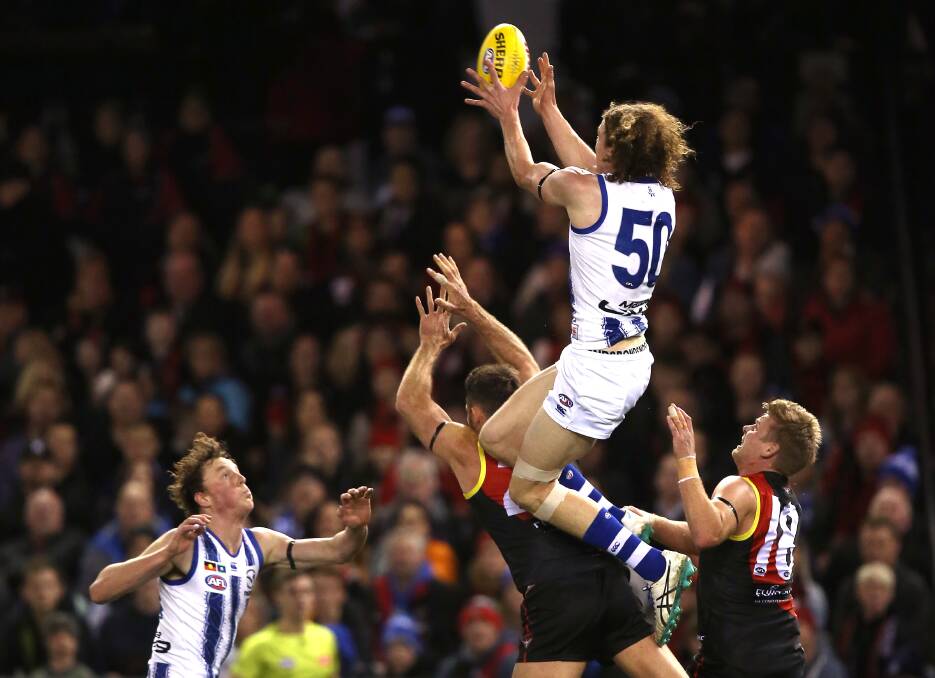 BIG GRAB: Ben Brown flies high against Cale Hooker and Michael Hurley in North Melbourne's loss to Essendon on Saturday. Picture: Wayne Lubdey