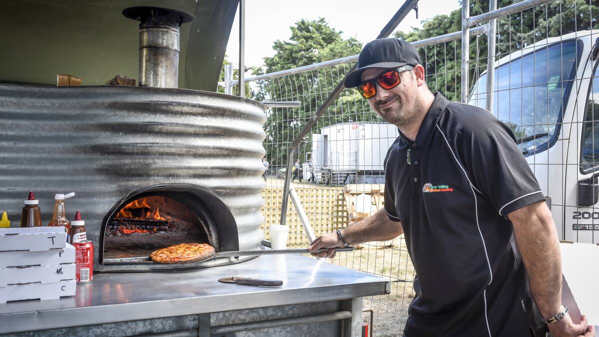 Nathan Barnett cooking a pizza on the woodfired ovens. Picture: Craig George
