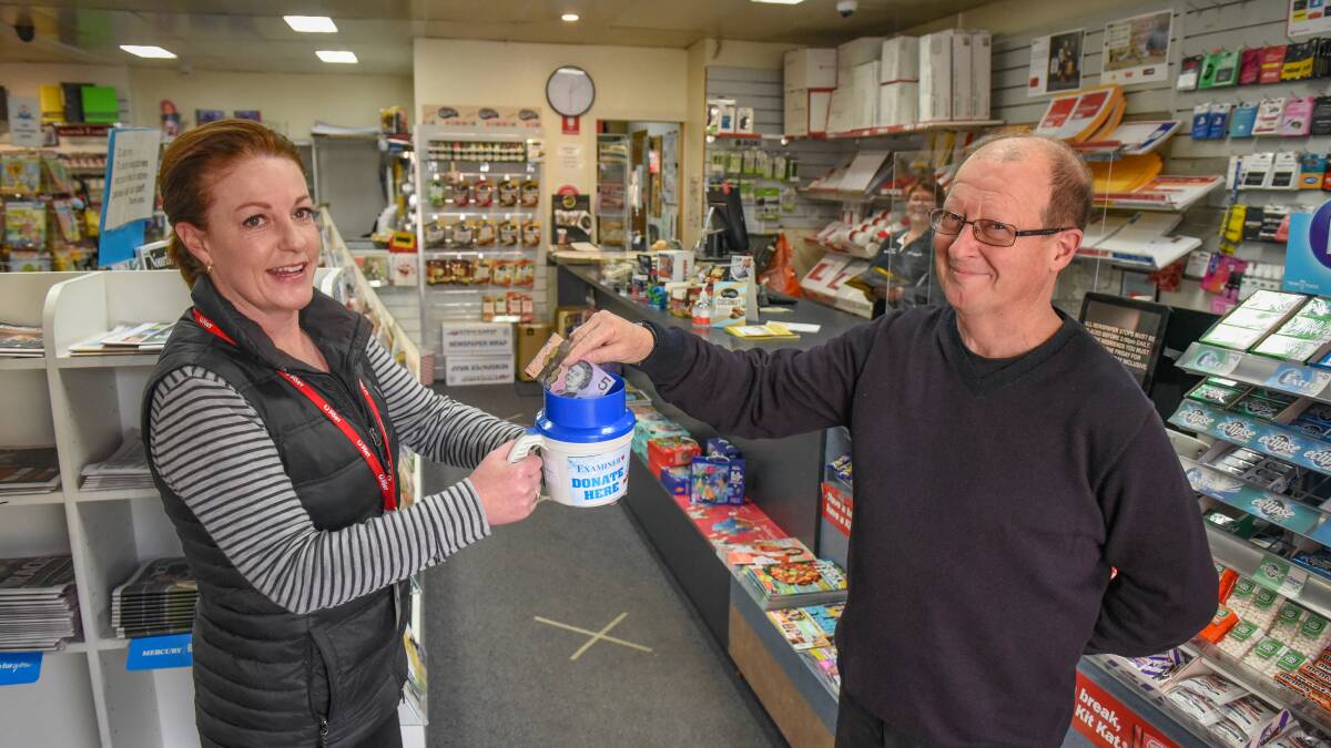 GIVING: Cathie Lewis, of Trevallyn Newsagency, holds a donation tin while Brendon Hextall gives some cash. Picture: Paul Scambler