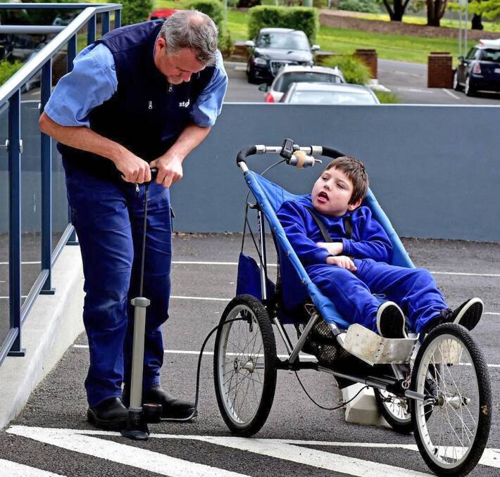 St Giles seating technician Shaun Lyall prepares Jack Duffy's wheelchair for the 14-kilometre Mount Barrow Challenge. Photo: Neil Richardson
