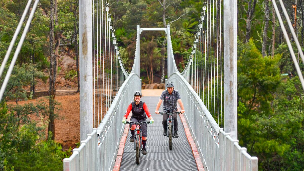 Peddling ahead: Vertigo MTB's Kerry Costello and Buck Gibson cross the recently opened Briseis Bridge on the Blue Derby mountain bike trails. Picture: Scott Gelston