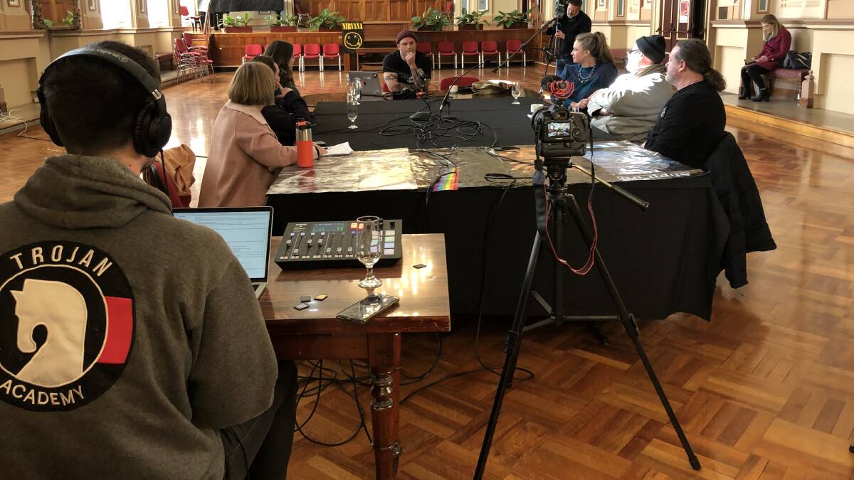 Podcaster Darran Petty sits at the head of a table on a discussion on homelessness in Tasmania.