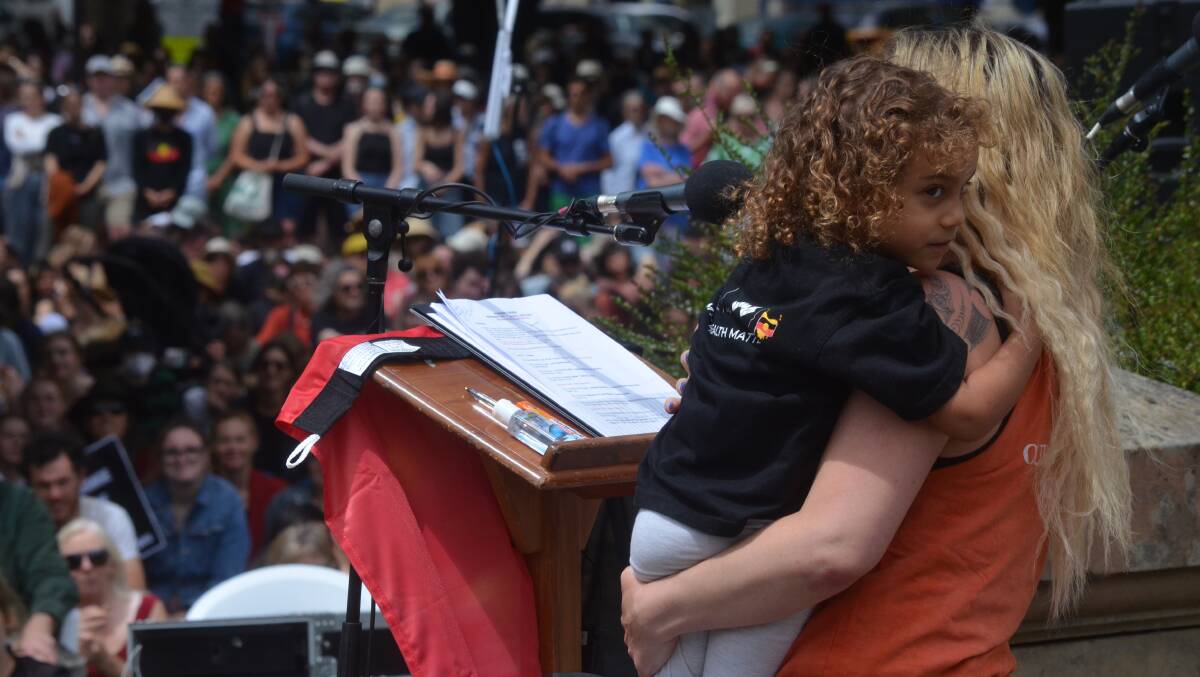 Activist Nala Mansell holds a Tasmanian Aboriginal child as she addresses a rally to protest a date change for Australia Day.